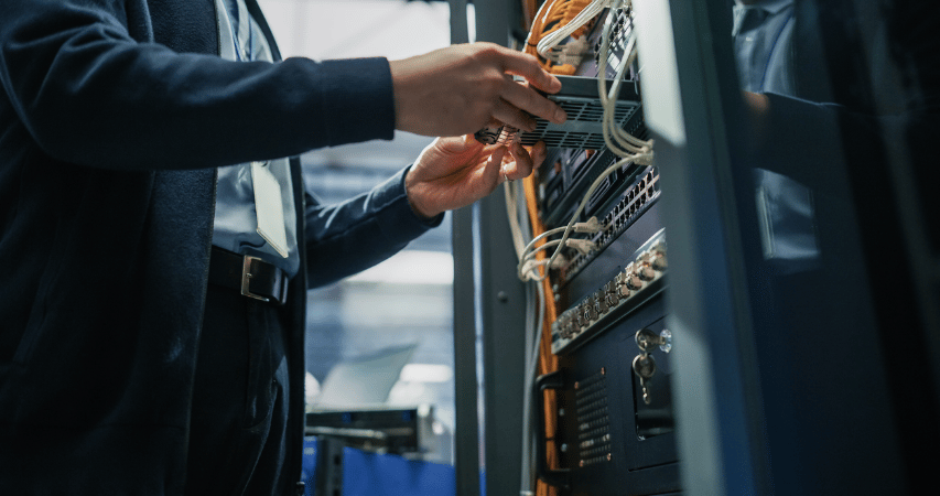 Male Engineer Hands Connecting Fiber Optic Cable Into Server Rack Patch Panel