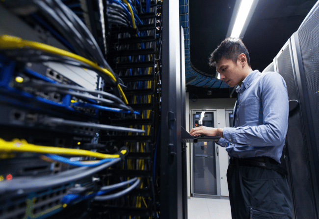 man with laptop servicing data centre